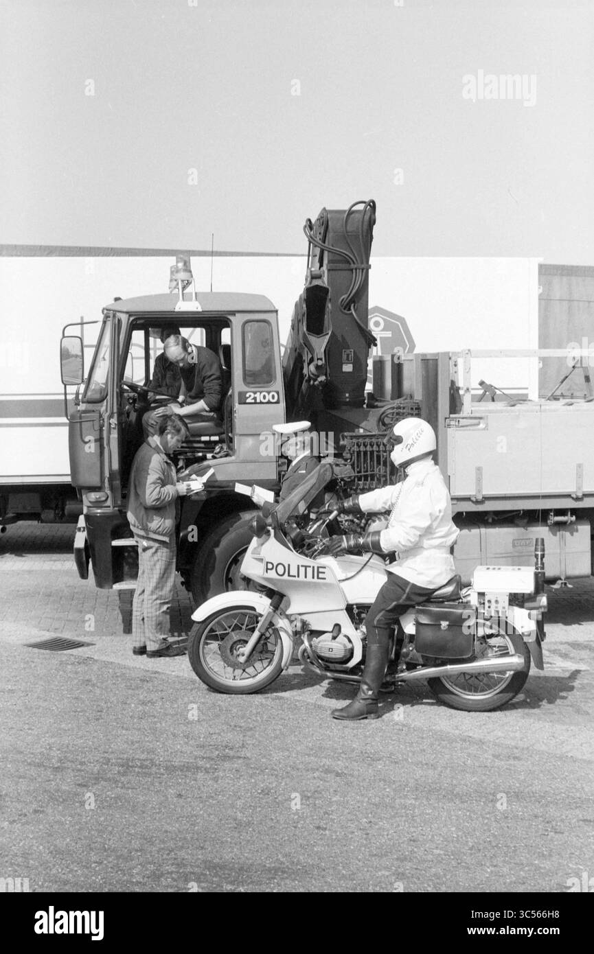 Camion di controllo della polizia A-9- Rick's bridge rest., polizia, 07-05-1987 Whizgle News, Dutch Desk, Paesi Bassi, 1950-2000 Un agente di polizia su una motocicletta interagisce con due persone con un grande camion, dato che una persona sembra fornire informazioni o documentazione. La scena suggerisce un momento di ispezione o controllo del traffico. Foto Stock