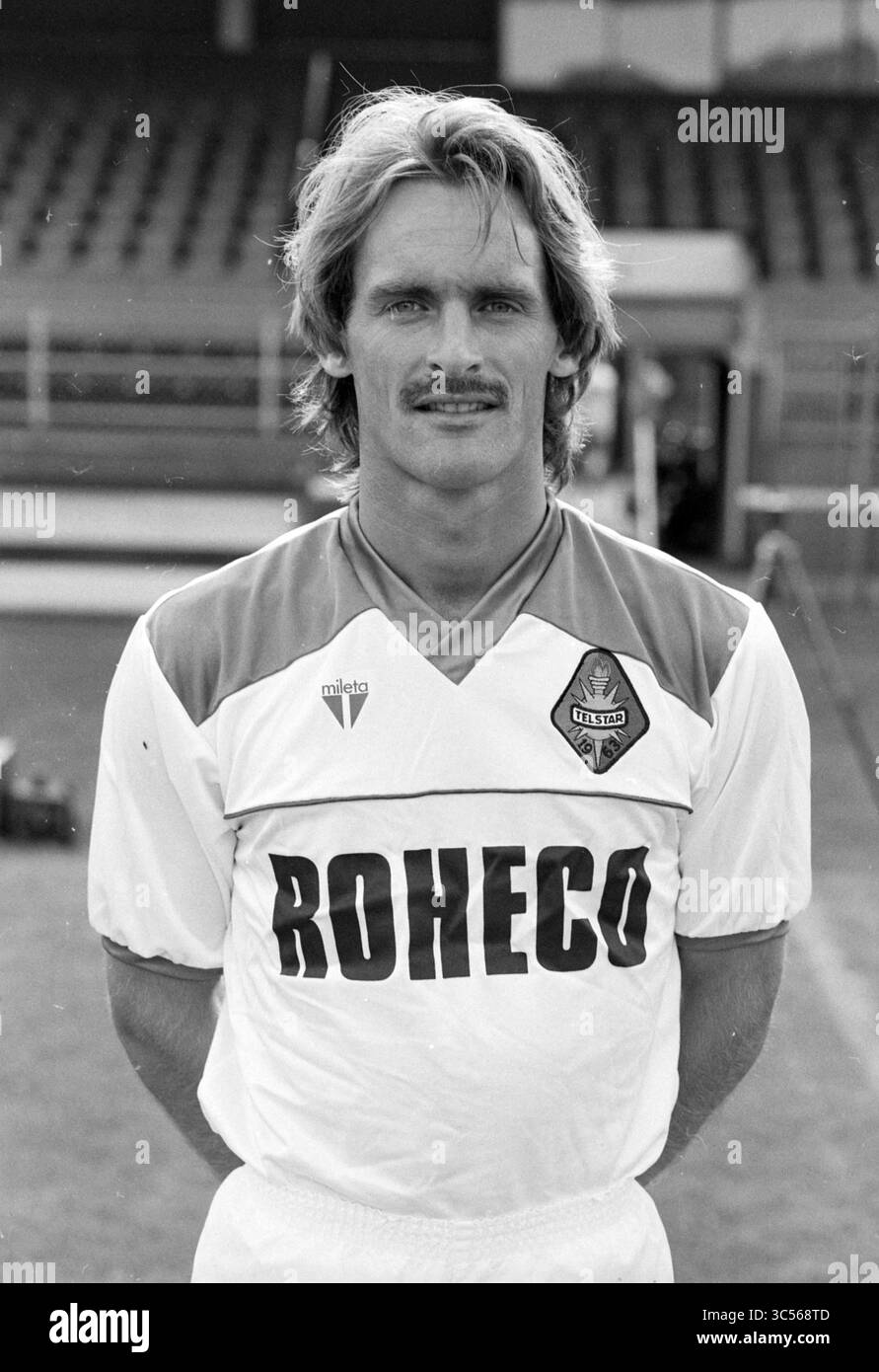 Giocatori e tabellone Telstar, 06-08-1991 Whizgle News, Dutch Desk, Paesi Bassi, 1950-2000 Un uomo si erge con fiducia in un'uniforme sportiva con il nome "ROHECO", che mostra un'acconciatura e baffi distinti. Sembra pronto, probabilmente rappresentando una squadra di calcio, con un comportamento atletico e uno sfondo che suggerisce una sede sportiva. Foto Stock