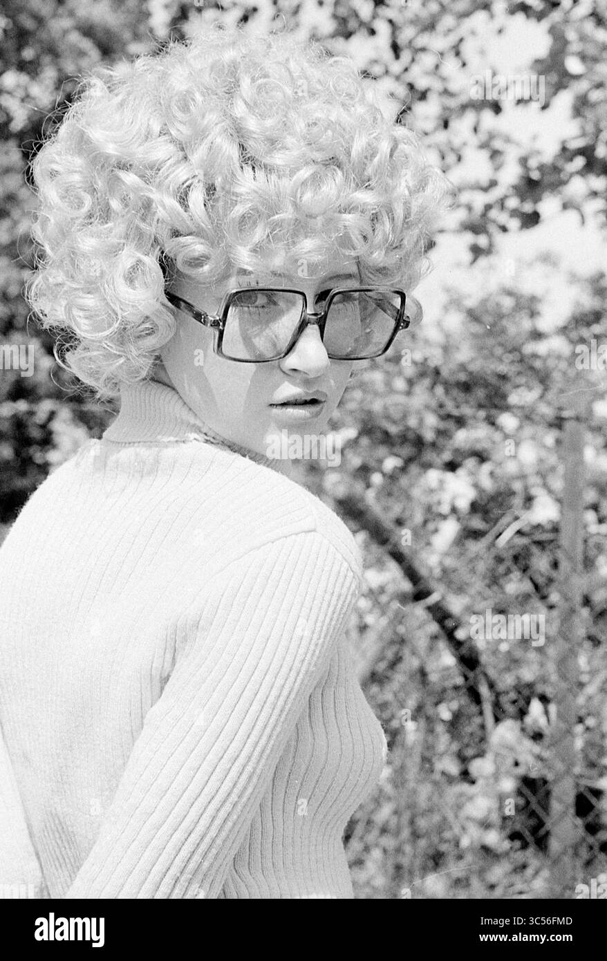 Models Loe-Loe, Models, 29-05-1971 Whizgle News, Dutch Desk, Paesi Bassi, 1950-2000 Una persona con capelli voluminosi e ricci e occhiali oversize torna ad affrontare lo spettatore, vestito con un maglione aderente sullo sfondo del verde. Foto Stock