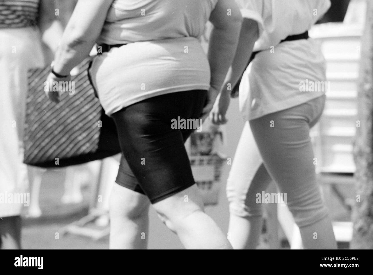 Occhiali da sole e pantaloncini corti e gonna corta, 05-07-1991 Whizgle News, Dutch Desk, Paesi Bassi, 1950-2000 Un gruppo di persone in abbigliamento casual cammina insieme, mostrando una varietà di stili di moda e movimenti, catturando un momento della vita quotidiana. Foto Stock