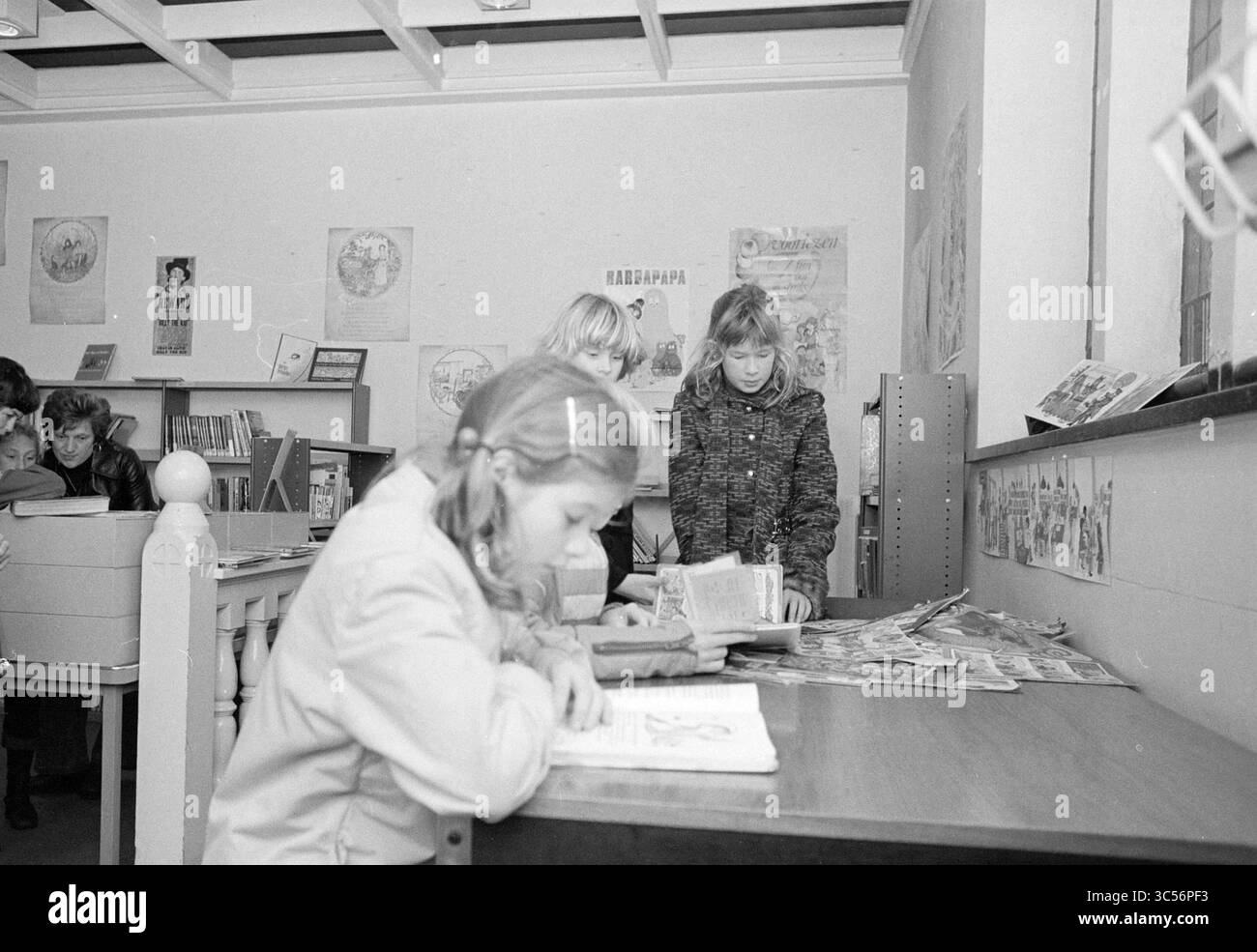 Riapertura del centro comunitario di Zandvoort, del Consiglio municipale di Zandvoort, apertura, messa in funzione, 05-11-1976 Whizgle News, Dutch Desk, Paesi Bassi, 1950-2000 Un gruppo di bambini è impegnato in varie attività in una biblioteca. Una ragazza si siede a un tavolo, leggendo intensamente un libro, mentre altre esplorano gli scaffali ed esaminano i materiali nelle vicinanze. L'ambiente è pieno di poster educativi, creando un'atmosfera vivace per l'apprendimento e la scoperta. Foto Stock