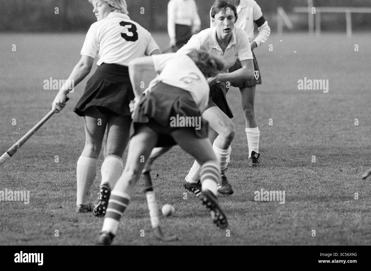 Fragole - Deventer Ladies, Hockey, 13-11-1983 Whizgle News, Dutch Desk, Paesi Bassi, 1950-2000 Un momento dinamico sul campo cattura i giocatori in azione durante una partita di hockey su prato, con un atleta che tenta abilmente di acquisire il controllo della palla mentre i compagni di squadra si posizionano per giocare in modo strategico. Le uniformi mostrano numeri, evidenziando l'atmosfera competitiva. Foto Stock