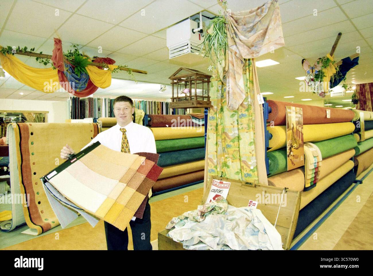 Spark and Floor, Cruquius, Cruquius, 07-09-1998 Whizgle News, Dutch Desk, i Paesi Bassi, 1950-2000 Un uomo ben vestito ha una tavolozza di colori, in un interno spazioso pieno di rotoli di tessuto e tessuti vivaci. Il decor pende dal soffitto, aggiungendo un tocco vivace all'invitante atmosfera del negozio di tessuti. Foto Stock