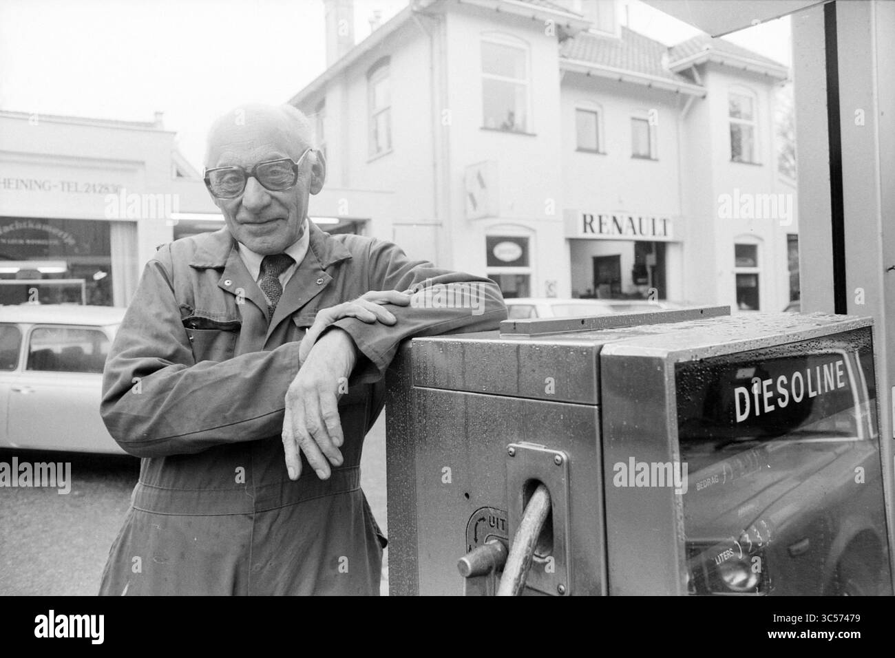 Uomo al distributore di benzina background: Concessionario Renault, 00-00-1986 Whizgle News, Dutch Desk, Paesi Bassi, 1950-2000 Un uomo in abito da lavoro si appoggia casualmente contro una pompa di carburante vintage, trasudando un senso di nostalgia ed esperienza. Dietro di lui, una concessionaria mostra con orgoglio il logo Renault, mentre le auto d'epoca sono parcheggiate nelle vicinanze, suggerendo un'epoca passata di automobilismo. Foto Stock