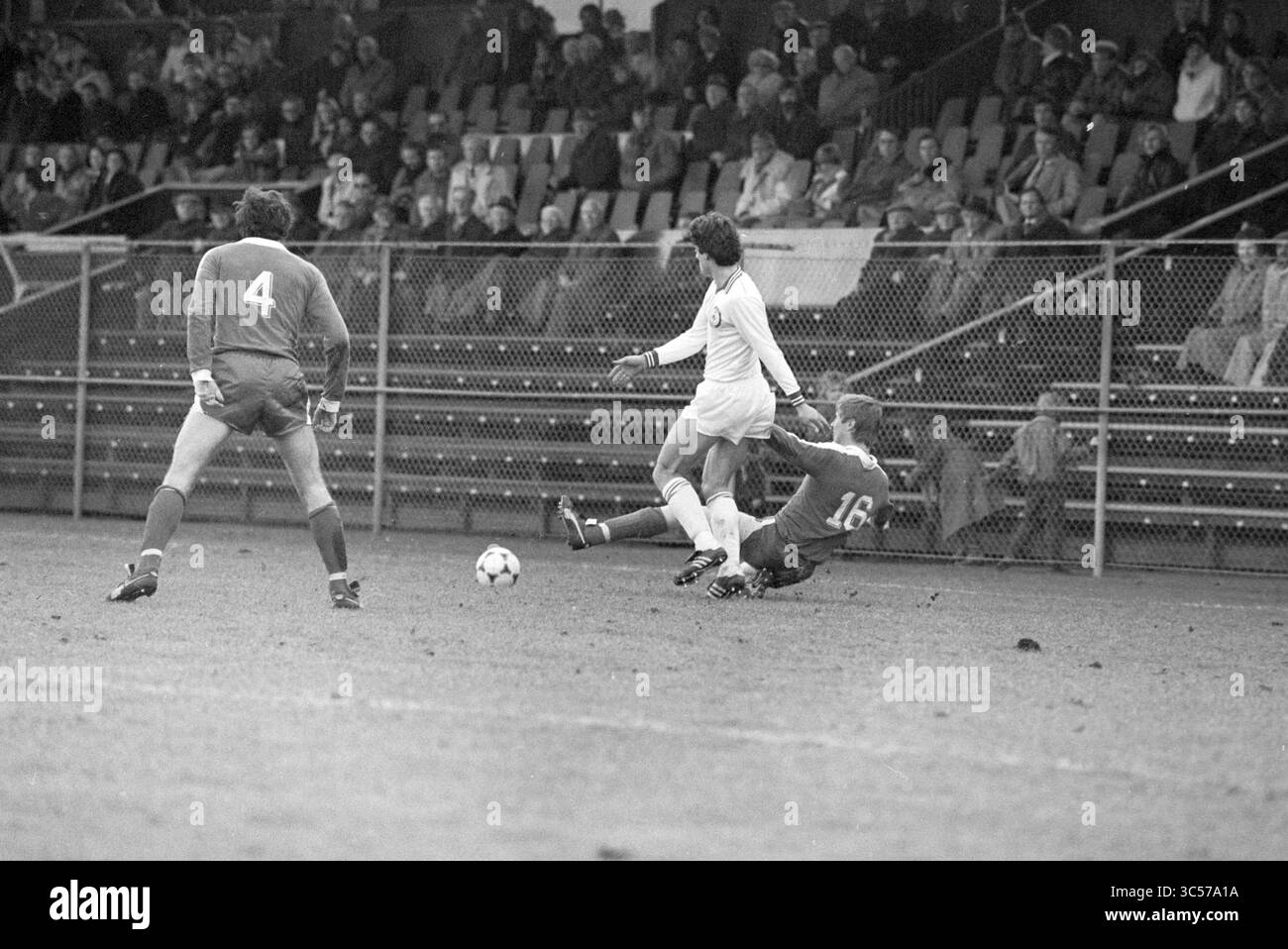 Telstar - Ufficio Turistico, calcio Telstar, 18-01-1981 Whizgle News, Dutch Desk, Paesi Bassi, 1950-2000 Un giocatore di calcio dribbla abilmente davanti a un avversario, mentre il portiere si prepara a difendersi da un gioco potenziale. Sullo sfondo, gli spettatori sono seduti in uno stadio, concentrati sull'azione che si svolge sul campo. Foto Stock