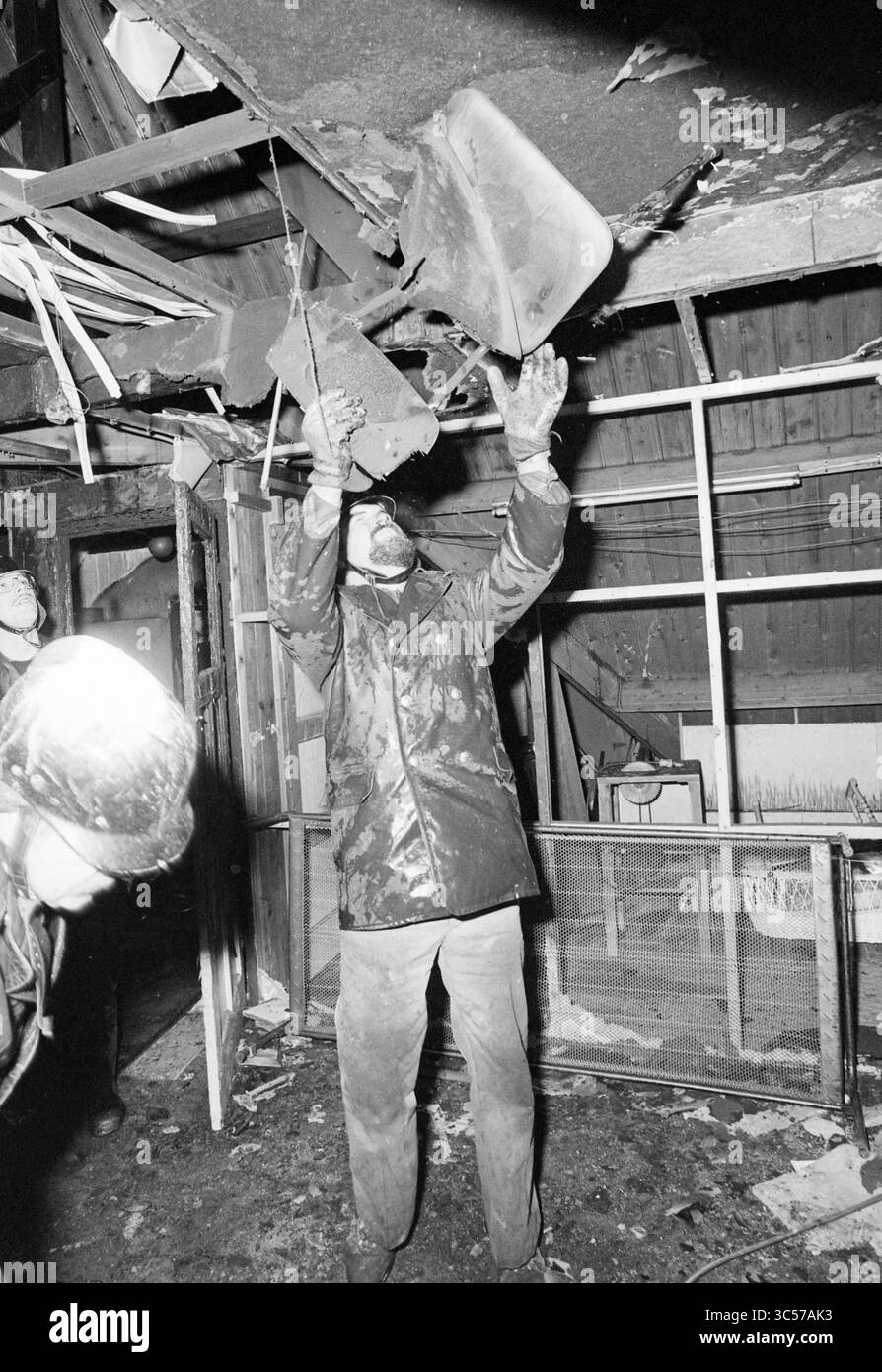 Pavimento bruciato di Valkenburgerlaan Heemstede, incendi, vigili del fuoco, Heemstede, Valkenburgerplein, paesi Bassi, 01-03-1981 Whizgle News, Dutch Desk, Paesi Bassi, 1950-2000 Un vigile del fuoco ispeziona i detriti che cadono dal soffitto in seguito all'incendio, mostrando i gravi danni all'interno di un interno carbonizzato. Un altro vigile del fuoco si trova nelle vicinanze, monitorando la situazione man mano che l'intenso lavoro di recupero continua. Foto Stock