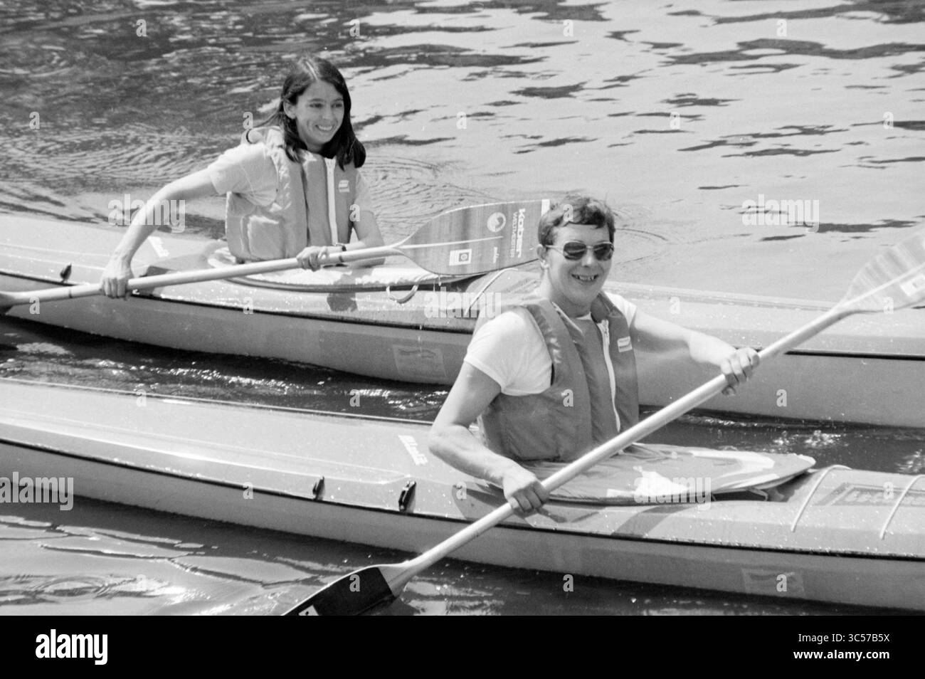 Canoeists in the Leidsevaart, Canoe, 07-07-1981 Whizgle News, Dutch Desk, Paesi Bassi, 1950-2000 due persone si stanno godendo una piacevole gita in kayak sulle acque calme, indossando giubbotti di salvataggio e sorridendo mentre pagaiano fianco a fianco. Il vibrante paesaggio riflette la gioia dell'avventura all'aria aperta e del cameratismo. Foto Stock