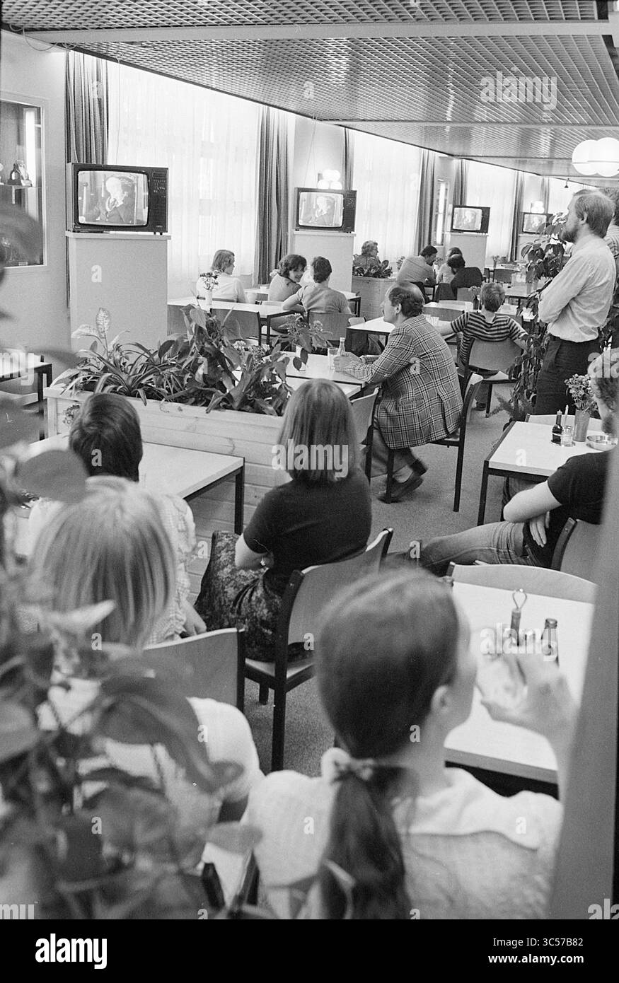Circuito TV Philips all'addio del sindaco Samkalden Amsterdam, Philips, 26-05-1977 Whizgle News, Dutch Desk, Paesi Bassi, 1950-2000 Un gruppo di persone si siede in uno spazio informale per pranzare, guardando con attenzione diversi televisori che trasmettono un programma. La camera presenta un decor semplice con piante e una varietà di disposizioni dei posti a sedere, creando un'atmosfera rilassata. Le conversazioni si interrompono mentre il pubblico si concentra sugli schermi, evidenziando un momento di interesse condiviso. Foto Stock Circuito TV Philips all'addio del sindaco Samkalden Amsterdam, Philips, 26-05-1977 Whizgle News, Dutch Desk, Paesi Bassi, 1950-2000 Un gruppo di persone si siede in uno spazio informale per pranzare, guardando con attenzione diversi televisori che trasmettono un programma. La camera presenta un decor semplice con piante e una varietà di disposizioni dei posti a sedere, creando un'atmosfera rilassata. Le conversazioni si interrompono mentre il pubblico si concentra sugli schermi, evidenziando un momento di interesse condiviso. Foto Stock