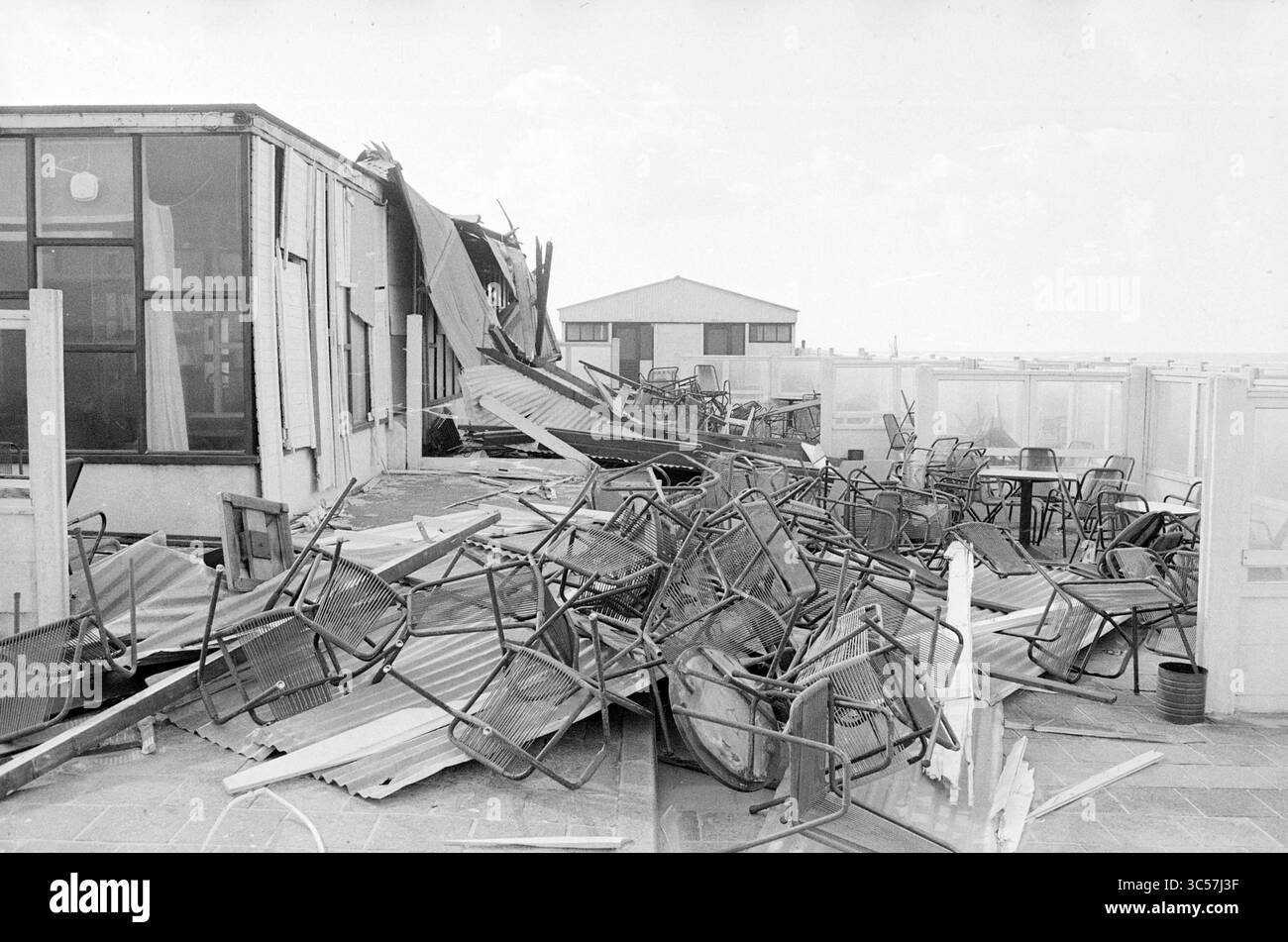 Padiglioni soffiati dal vento sul viale Bloemendaal e sulla spiaggia, Ravage, 28-09-1975 Whizgle News, Dutch Desk, Paesi Bassi, 1950-2000 Una scena di distruzione rivela un edificio con un tetto crollato, detriti sparsi intorno e sedie rovesciate disseminate sul pavimento, a indicare un recente disastro o un grave evento meteorologico. Foto Stock