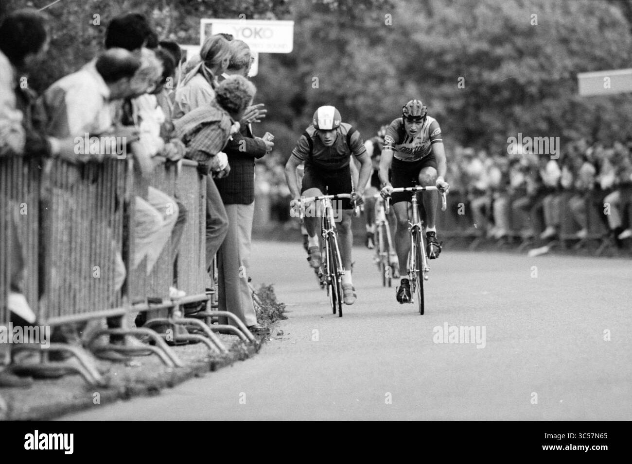 Atmosfera e competizione round coppa di Bloemendaal, ciclismo, Bloemendaal, 06-07-1988 Whizgle News, Dutch Desk, i Paesi Bassi, 1950-2000 due ciclisti corrono intensamente fianco a fianco, in competizione per il comando. Gli spettatori entusiasti seguono il percorso, appoggiandosi sulle barriere, incoraggiandoli mentre si avvicinano a una curva della strada. L'atmosfera è elettrica con eccitazione e attesa. Foto Stock