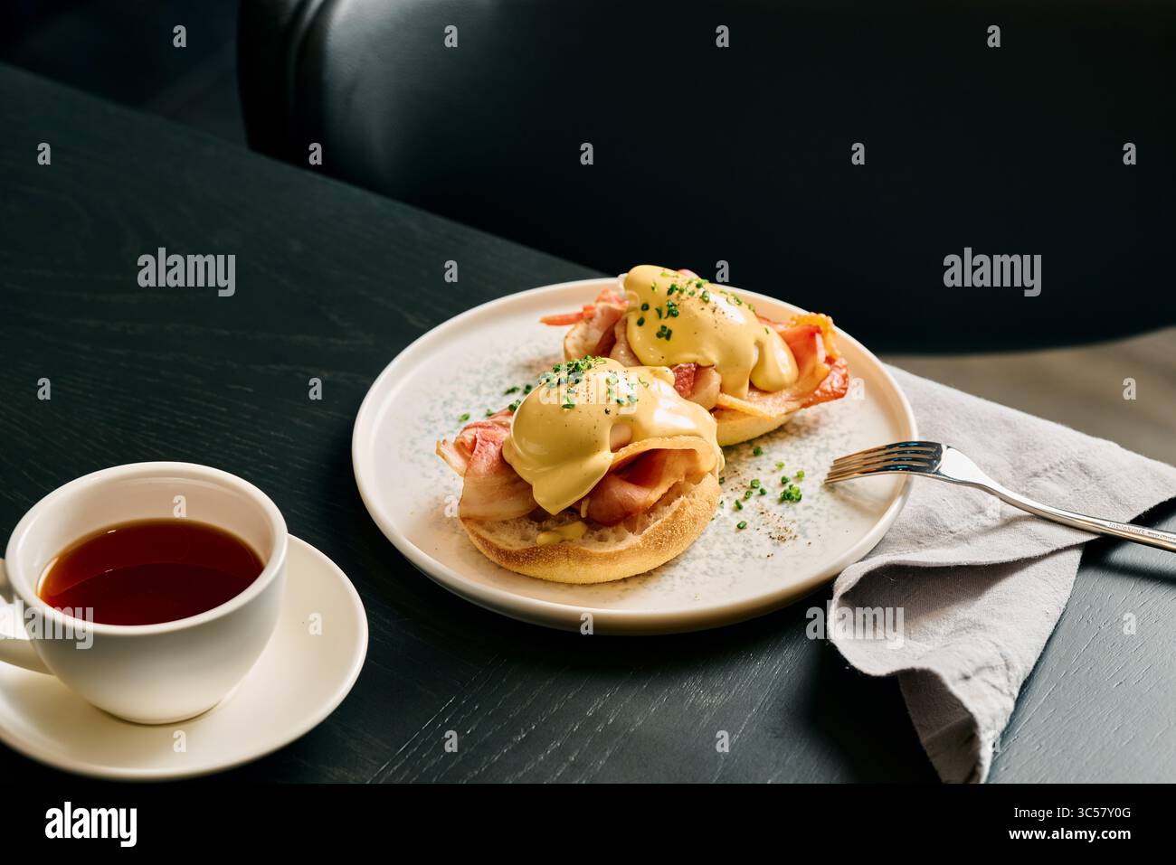 Uova da buongustai alla benedict con cremosa salsa hollandaise, pancetta croccante su muffin inglesi serviti con caffè fresco. Ottimo brunch in un raffinato bar. Foto Stock