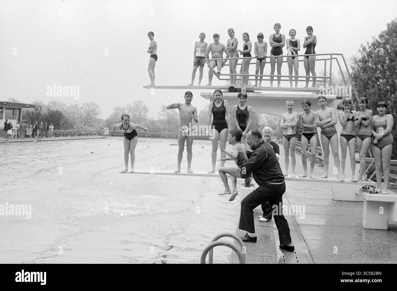 Apertura della stagione balneare Vosse Hillegom, apertura, messa in funzione, Hillegom, 04-05-1984 Whizgle News, Dutch Desk, Paesi Bassi, 1950-2000 Un gruppo di subacquei si prepara a una sessione di immersione sincronizzata in una piscina, con spettatori che guardano dalle tavole, mostrando una miscela di anticipazione e cameratismo in un ambiente vivace. Foto Stock