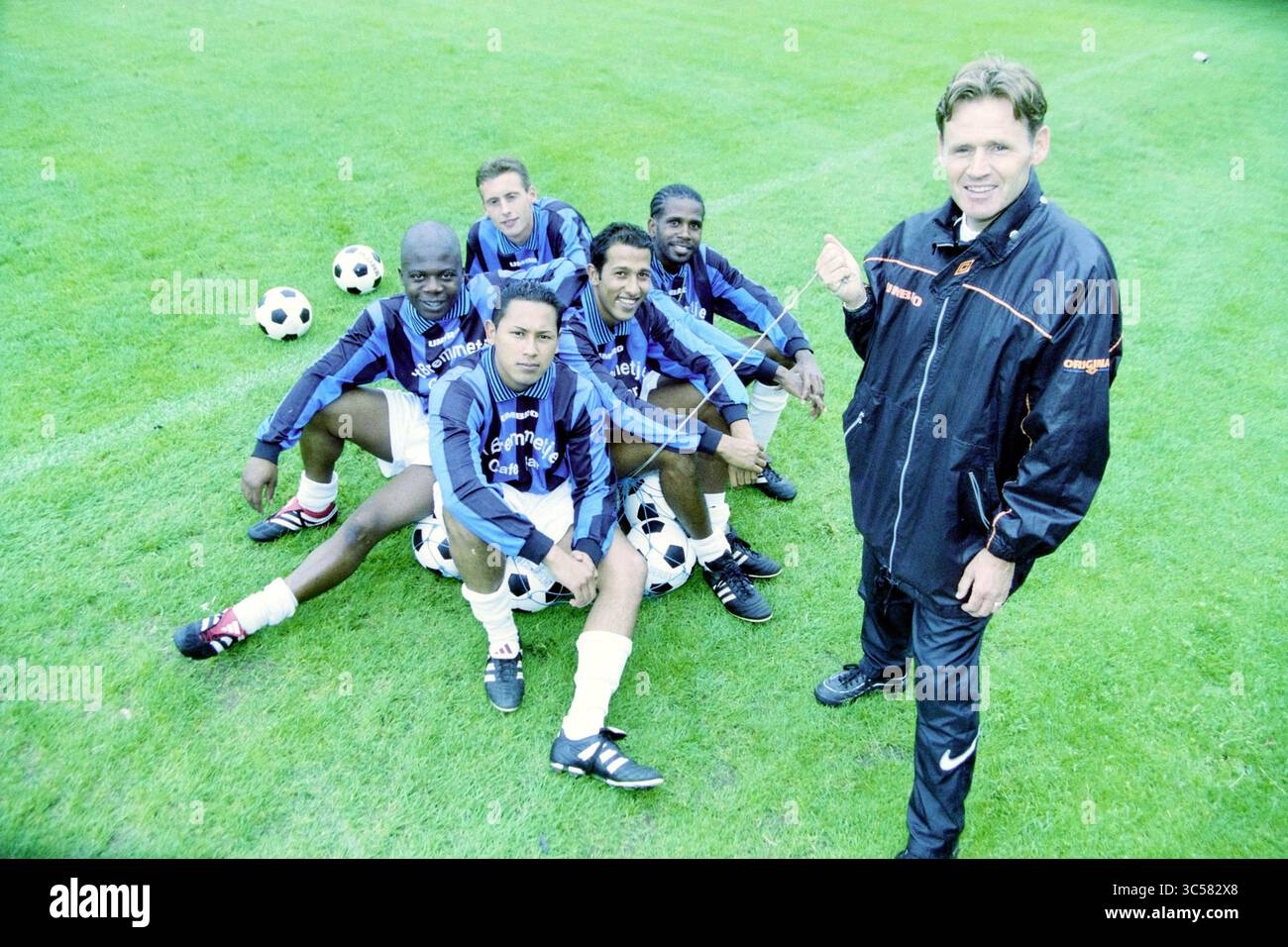RCH Players, Heemstede, Heemstede, Paesi Bassi, 12-08-2001 Whizgle News, Dutch Desk, Paesi Bassi, 1950-2000 Un gruppo di cinque giocatori di calcio posano con fiducia su un campo erboso, ognuno con un calcio, mentre il loro allenatore si trova accanto a loro, sorridendo e gestendo con entusiasmo. Le divise della squadra sono caratterizzate da top blu scuro con un logo accattivante, che mostra un senso di cameratismo e di prontezza per il gioco. Foto Stock