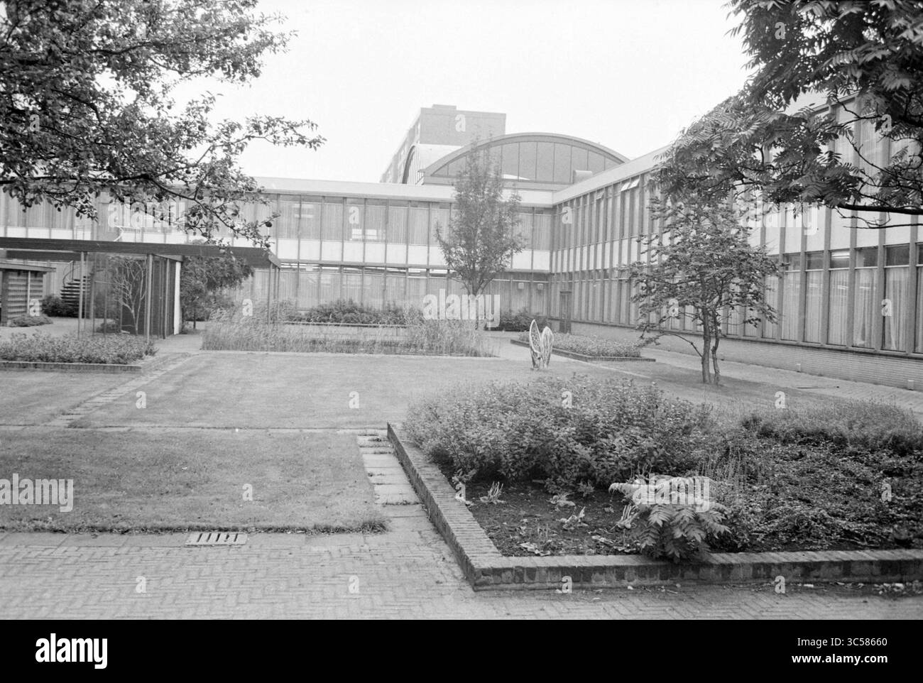 Courtyard Beverwijk City Office, Beverwijk Buildings, Gardens and Parks, Beverwijk, Paesi Bassi, 26-09-1979 Whizgle News, Dutch Desk, Paesi Bassi, 1950-2000 Un tranquillo cortile con prati ben rifiniti e macchie di verde, fiancheggiato da moderne strutture architettoniche con grandi finestre. L'ambiente trasuda un'atmosfera tranquilla e organizzata, evidenziata da alcuni alberi e piante che ne esaltano l'ambiente tranquillo. Foto Stock