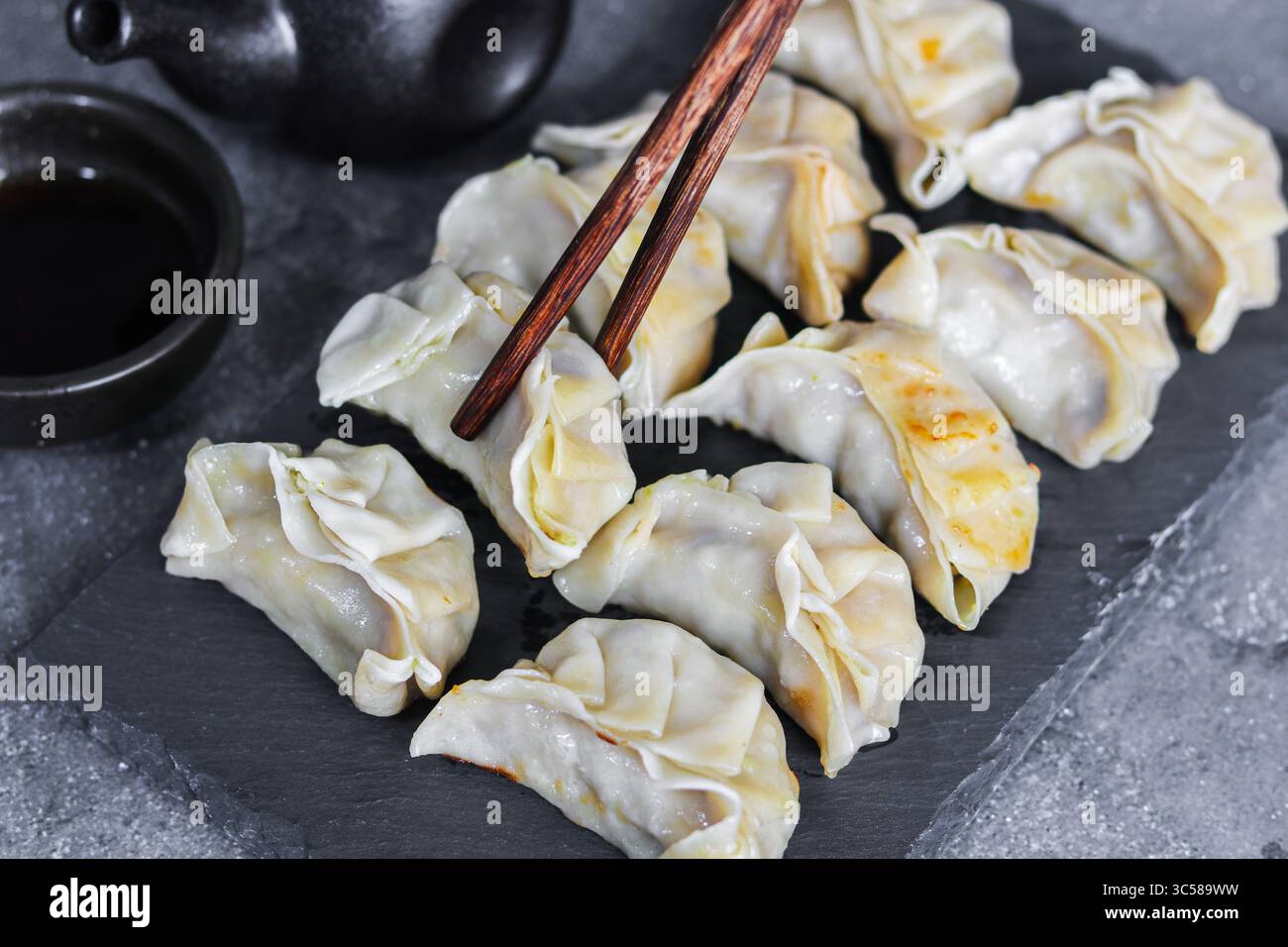 Deliziosi gyoza giapponesi, pronti per essere gustati con una salsa salata. Un antipasto o un pasto ideale da consumare con le bacchette. Foto Stock