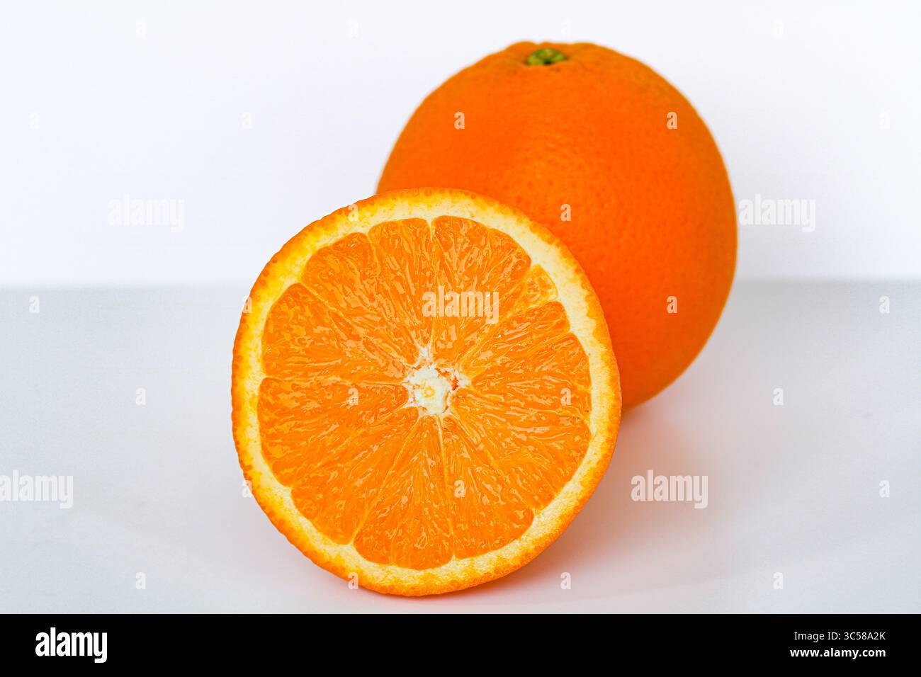 Vivaci arance sunkiste. Un intero intero, uno a metà, catturato con una luce nitida su uno sfondo bianco. Foto Stock