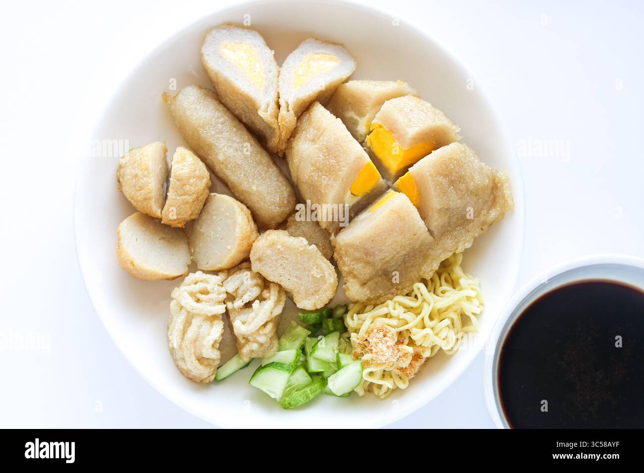 Una porzione di Pempek assortito (o Empek-Empek), un tradizionale piatto di torta di pesce indonesiano di Palembang, con spaghetti e cetrioli a fette. Foto Stock