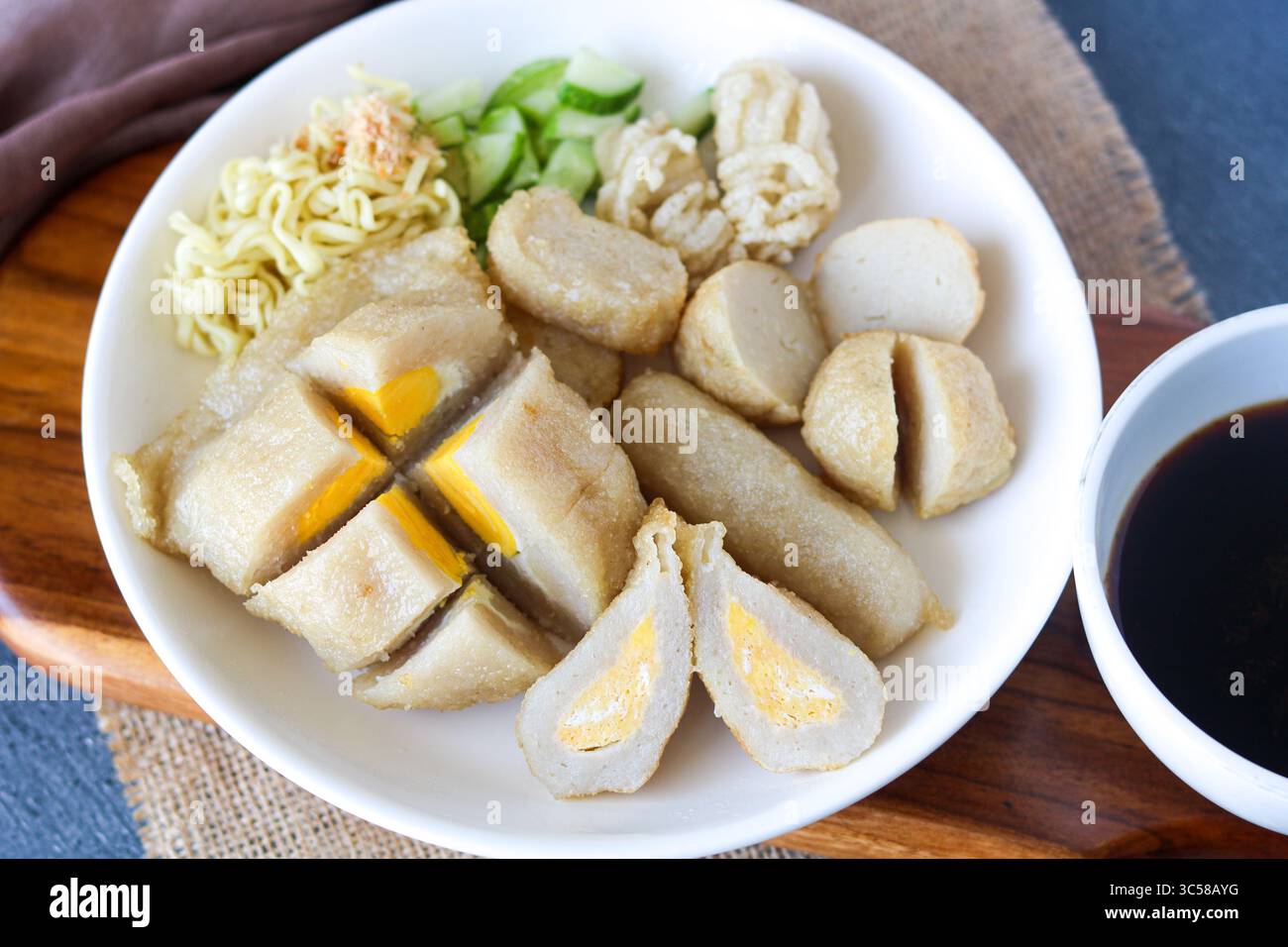Una porzione di Pempek assortito (o Empek-Empek), un tradizionale piatto di torta di pesce indonesiano di Palembang, con spaghetti e cetrioli a fette. Foto Stock