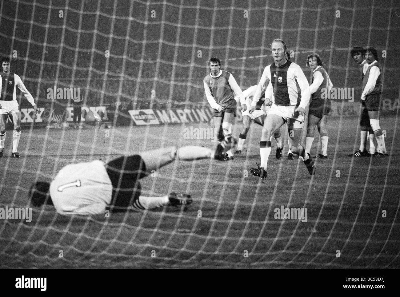FC Ajax - FC Feyenoord 6-0, Football Ajax, 01-11-1975 Whizgle News, Dutch Desk, Paesi Bassi, 1950-2000 Un momento congelato nel tempo cattura una partita di calcio tesa, con un giocatore che celebra un gol mentre il portiere avversario giace a terra, dopo essere stato appena segnato. Compagni di squadra e avversari guardano in vari stati di incredulità ed eccitazione. Foto Stock
