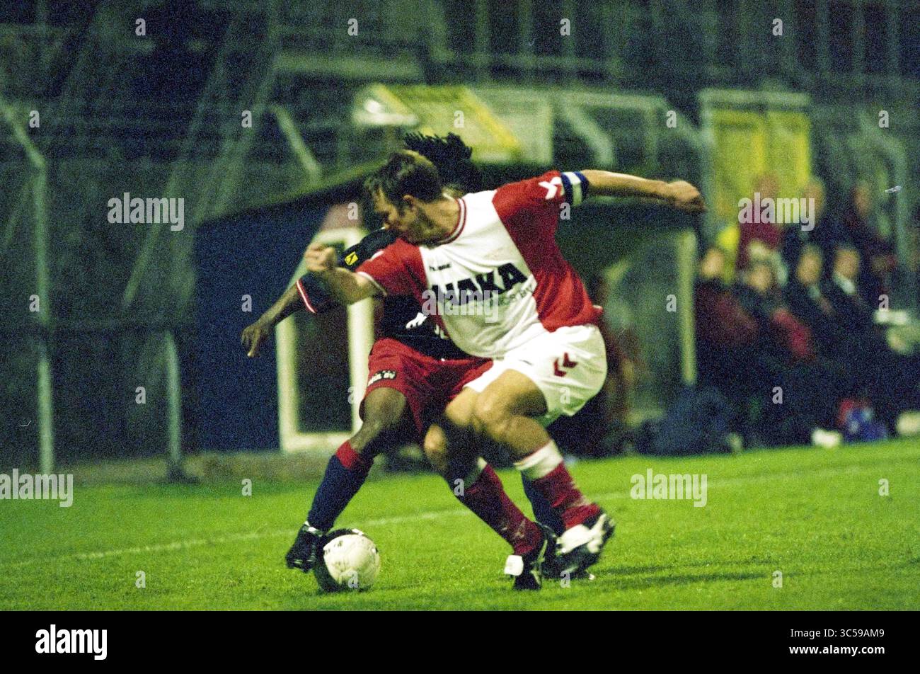 Calcio: Haarlem - Emmen, Haarlem, Paesi Bassi, 26-09-2002 Whizgle News, Dutch Desk, i Paesi Bassi, 1950-2000 due giocatori di calcio sono impegnati in un momento competitivo sul campo, con uno che tenta di riprendere il controllo del pallone mentre l'altro si spinge in avanti. L'intensità del gioco è evidente mentre si sforzano di superare l'uno dell'altro in mezzo allo sfondo di una folla acclamata. Foto Stock