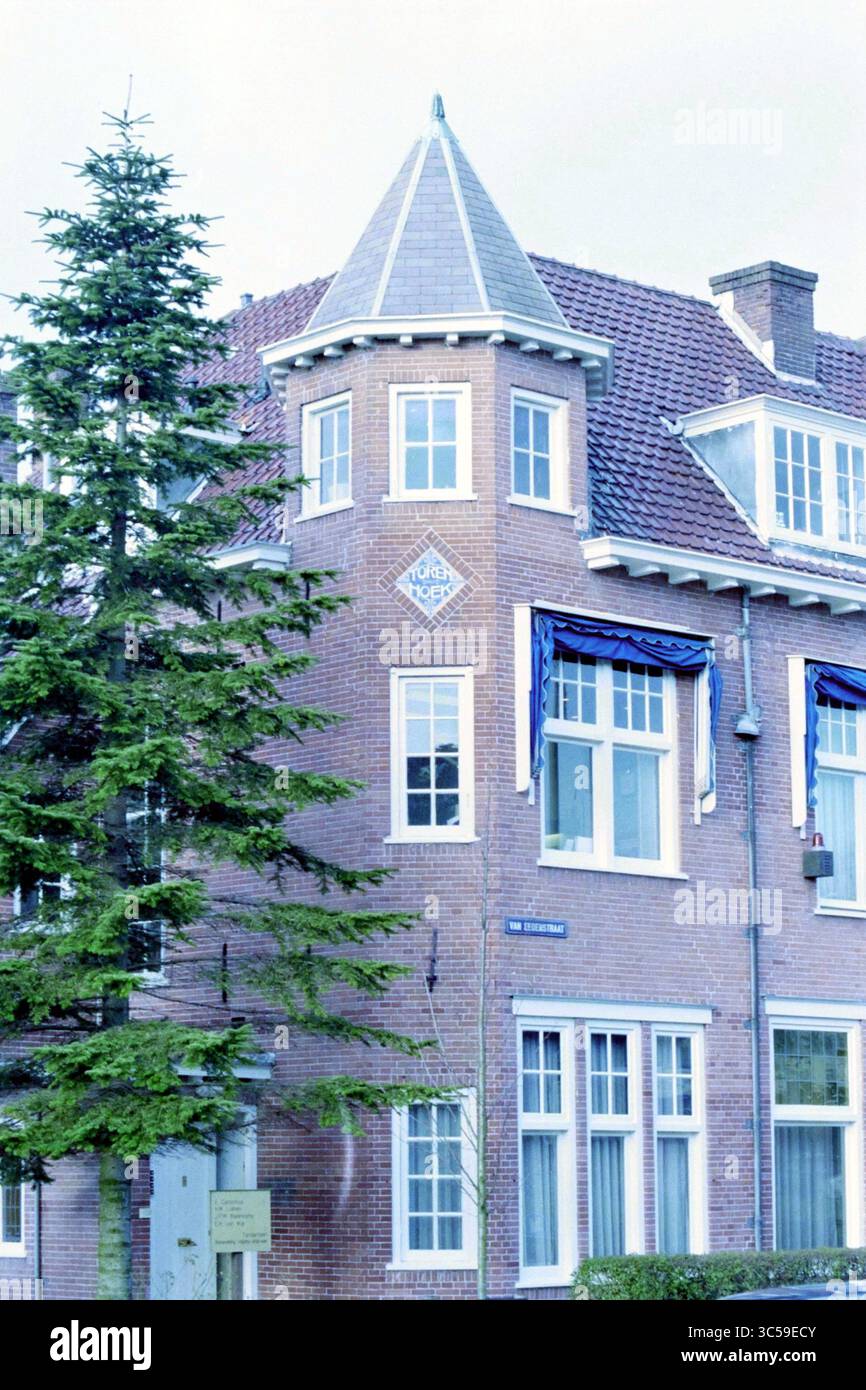 Tower Van Eedenstraat Haarlem [angolo Lakenkopersstraat], Haarlem, Van Eedenstraat, Paesi Bassi, 21-12-1998 Whizgle News, Dutch Desk, Paesi Bassi, 1950-2000 Un caratteristico edificio in mattoni presenta un tetto turrito con un emblema decorativo sopra una serie di grandi finestre. La struttura è incorniciata da un alto albero di conifere, che aggiunge al suo fascino affascinante. Foto Stock