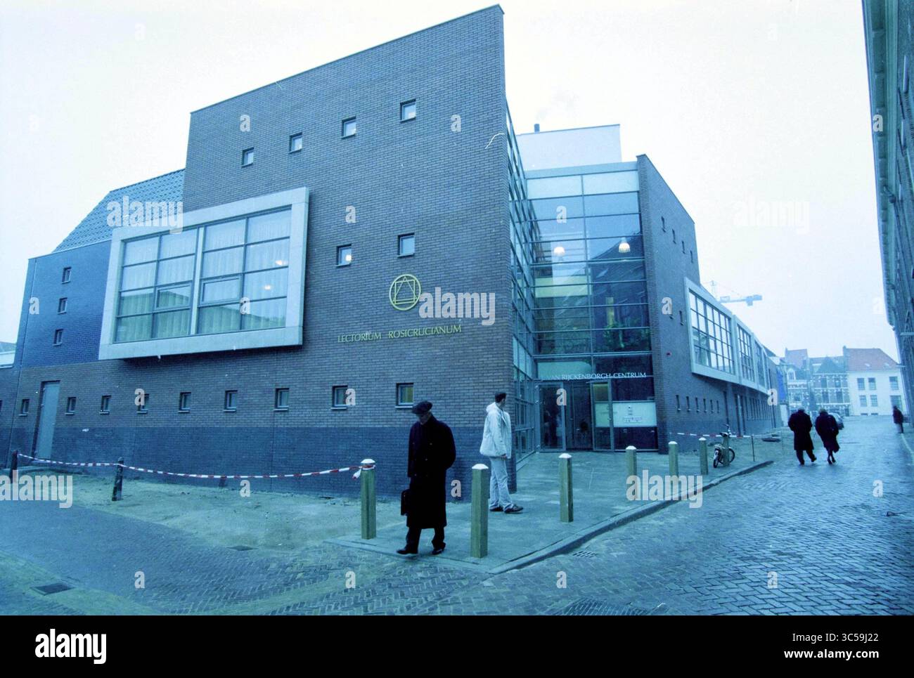 Rijckenborgh Center, Haarlem, Paesi Bassi, 13-12-2002 Whizgle News, Dutch Desk, i Paesi Bassi, 1950-2000 Un edificio moderno con una combinazione di mattoni e vetri sorge su una strada tranquilla. La struttura, contrassegnata da un emblema circolare, contrasta con l'architettura tradizionale che la circonda. I pedoni passeggiano nelle vicinanze, aggiungendo un senso di vita alla scena urbana. Foto Stock