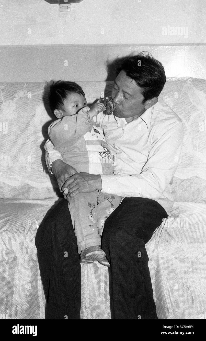 Momento d'allattamento di padre e bambino cinese vintage sul divano del soggiorno Foto Stock
