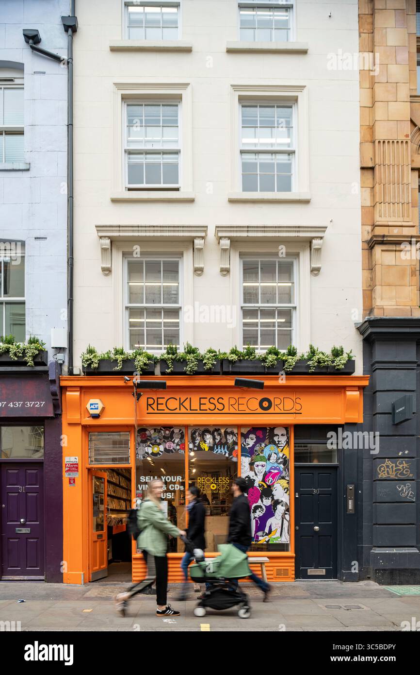 Vista sulla strada della Reckless Records in Berwick Street a Soho, Londra, con i pedoni che passano davanti al vivace negozio arancione del famoso negozio di vinile. Foto Stock
