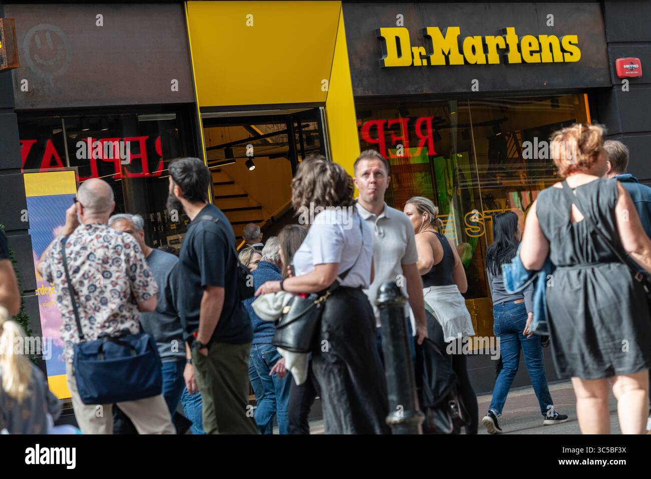 La folla passa accanto al negozio Dr. Martens sulla vivace Carnaby Street a Soho, Londra, una destinazione popolare per la moda, lo shopping e la cultura giovanile. Foto Stock