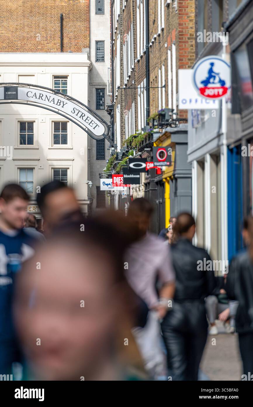 Cartellone di Carnaby Street con affollate folle e negozi iconici a Soho, Londra, una famosa destinazione per la moda e lo shopping nel West End. Foto Stock