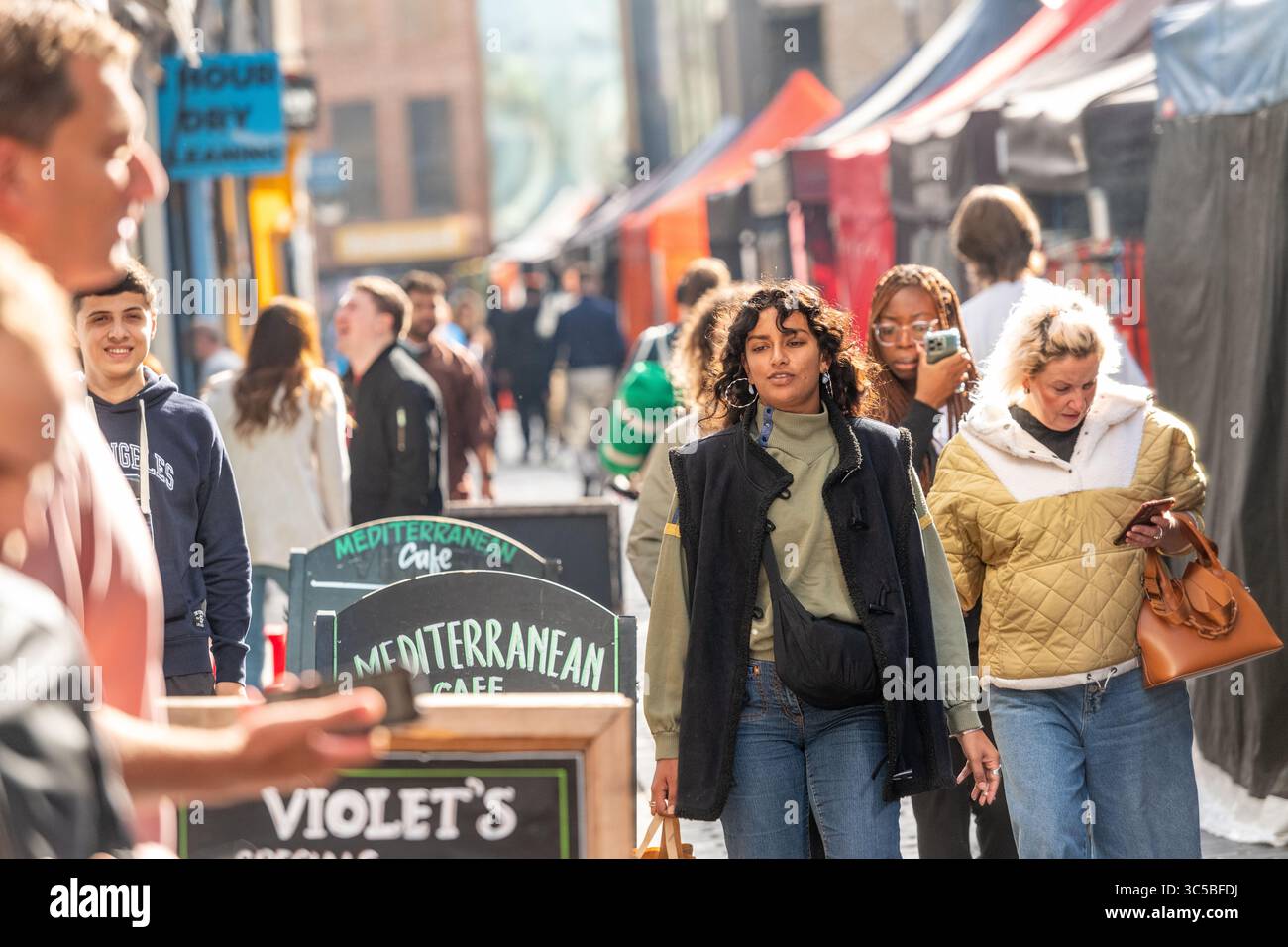 Il vivace mercato di Berwick Street a Soho, Londra, con pedoni, bancarelle di cibo e vivace vita di strada nel pomeriggio del fine settimana. Foto Stock