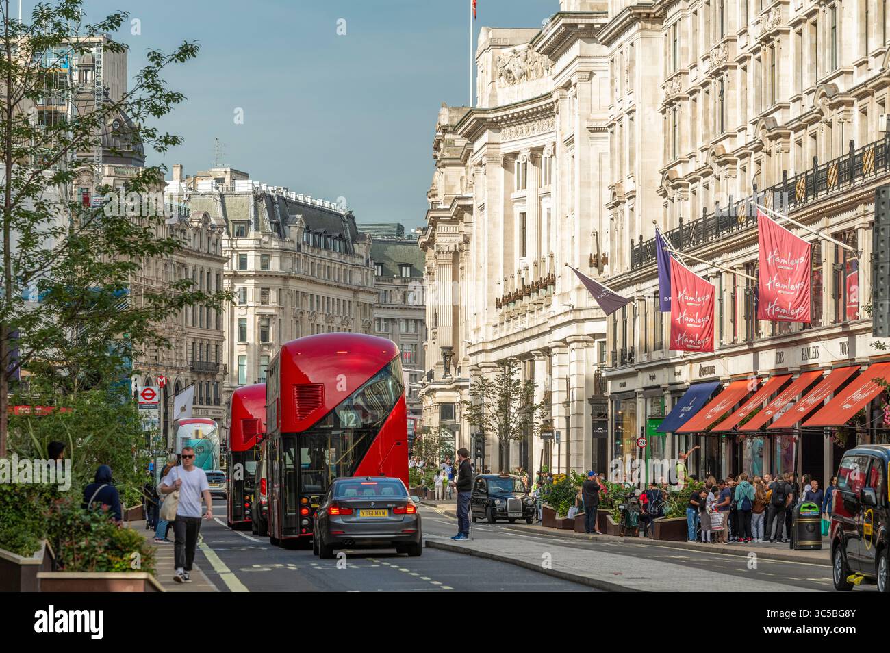 Autobus rossi a due piani e pedoni sulla trafficata Oxford Street, nel centro di Londra, in una luminosa giornata estiva nel vivace quartiere dello shopping del Regno Unito. Foto Stock