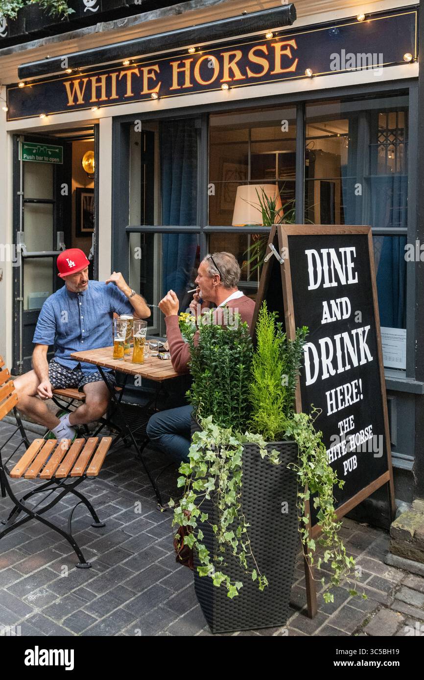 Due uomini si godono un drink fuori dal pub White Horse di Soho, Londra, un luogo popolare per socializzare all'aperto nel West End. Foto Stock