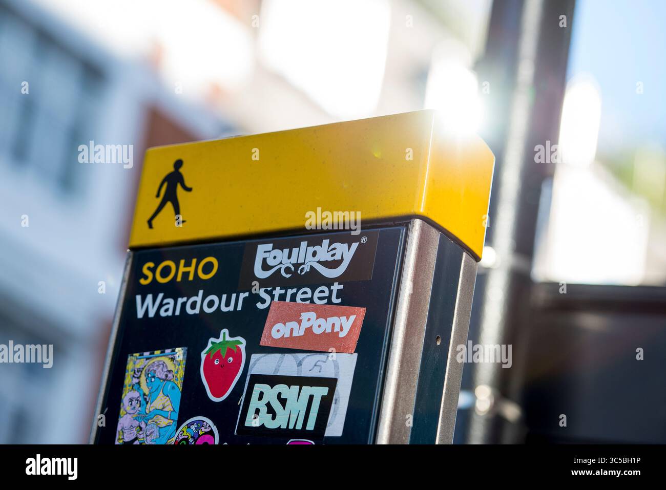 Primo piano di un cartello pedonale per Wardour Street a Soho, Londra, con luce solare e adesivi colorati in mostra. Foto Stock
