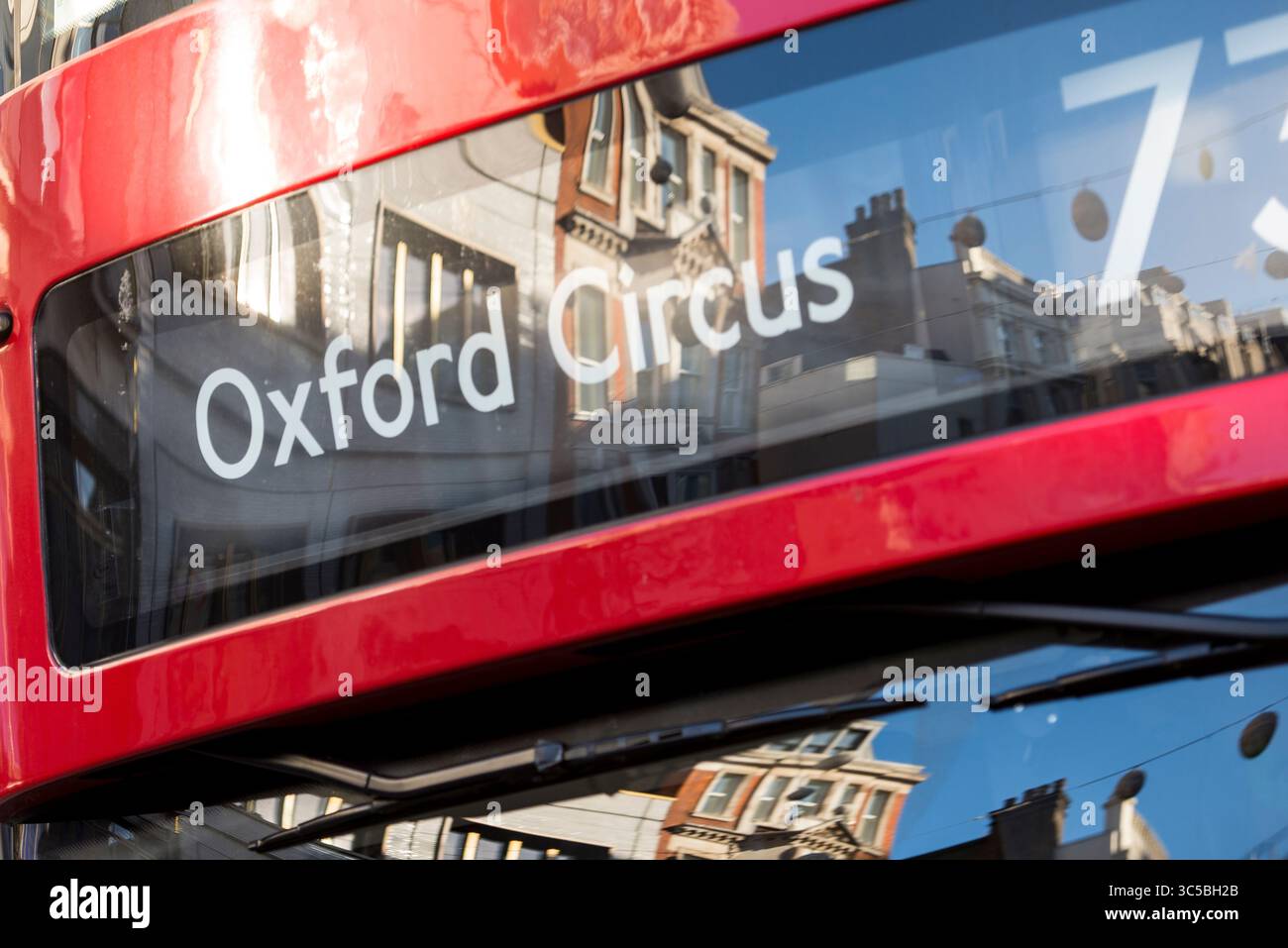 Riflessi dell'architettura di Oxford Street alla finestra di un autobus rosso a due piani che mostra la destinazione di Oxford Circus, nel centro di Londra. Foto Stock