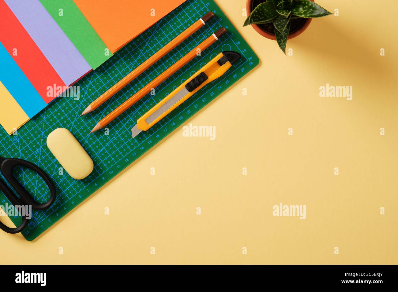 Forniture per hobby di arte cartacea: Forbici, coltello artigianale, matita, gomma, carta colorata. Spazio per il testo. La carta crea il piano del tavolo da lavoro. Foto Stock