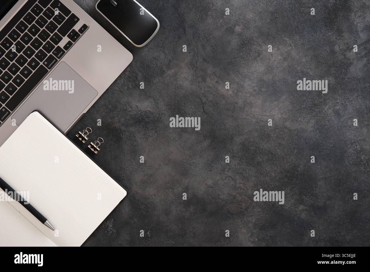 Spazio di lavoro minimalista con laptop, sistema di pianificazione proiettile nero, mouse per computer, penna su sfondo scuro. Copia spazio. Foto Stock