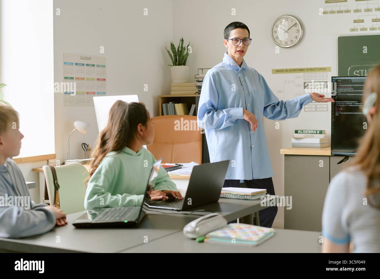 Donna caucasica di mezza età che insegna diversi adolescenti programmazione informatica Foto Stock