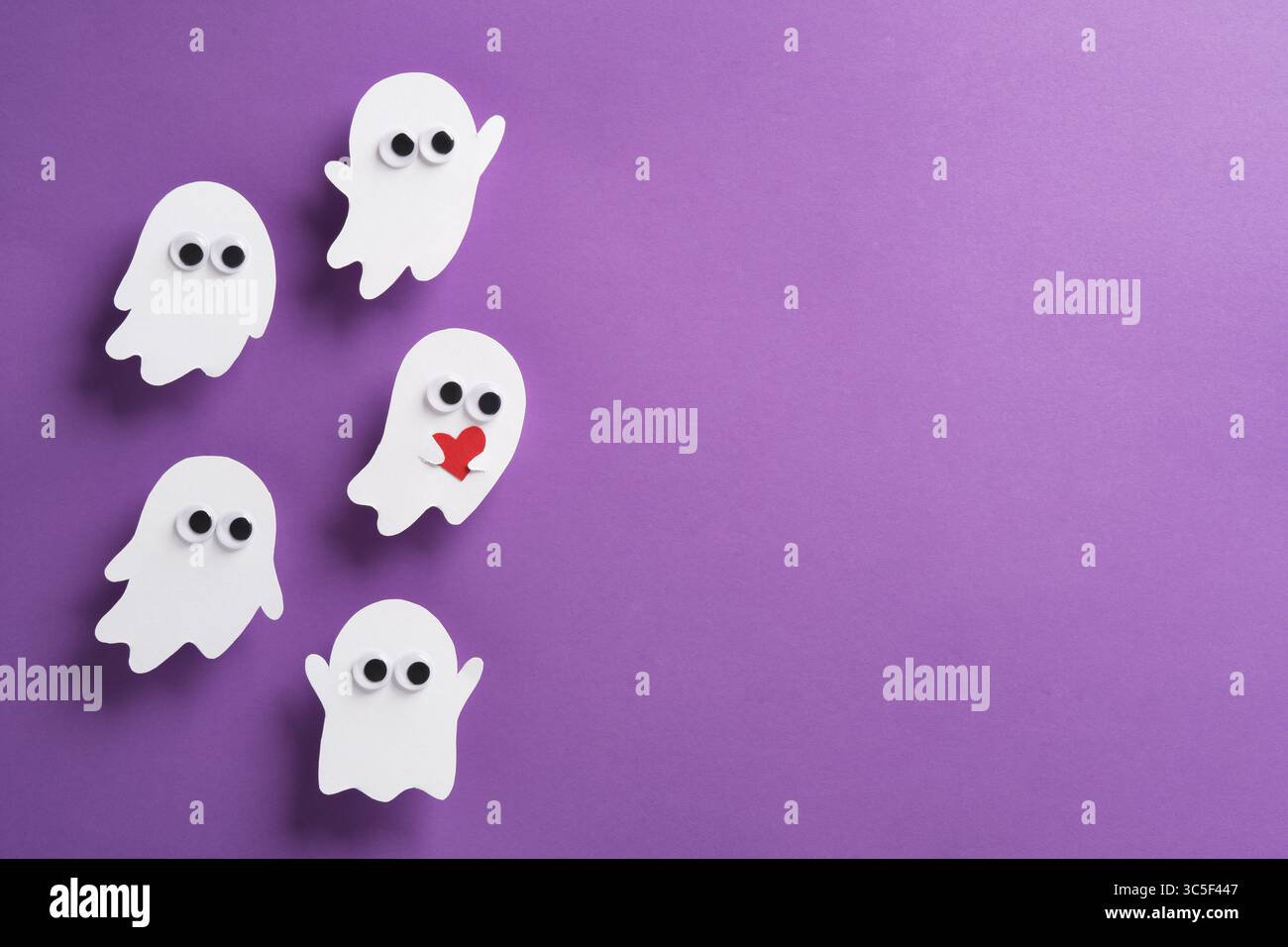 Simpatici fantasmi con occhi su sfondo viola, un fantasma con cuore rosso, banner orizzontale di Halloween, spazio per il testo Foto Stock