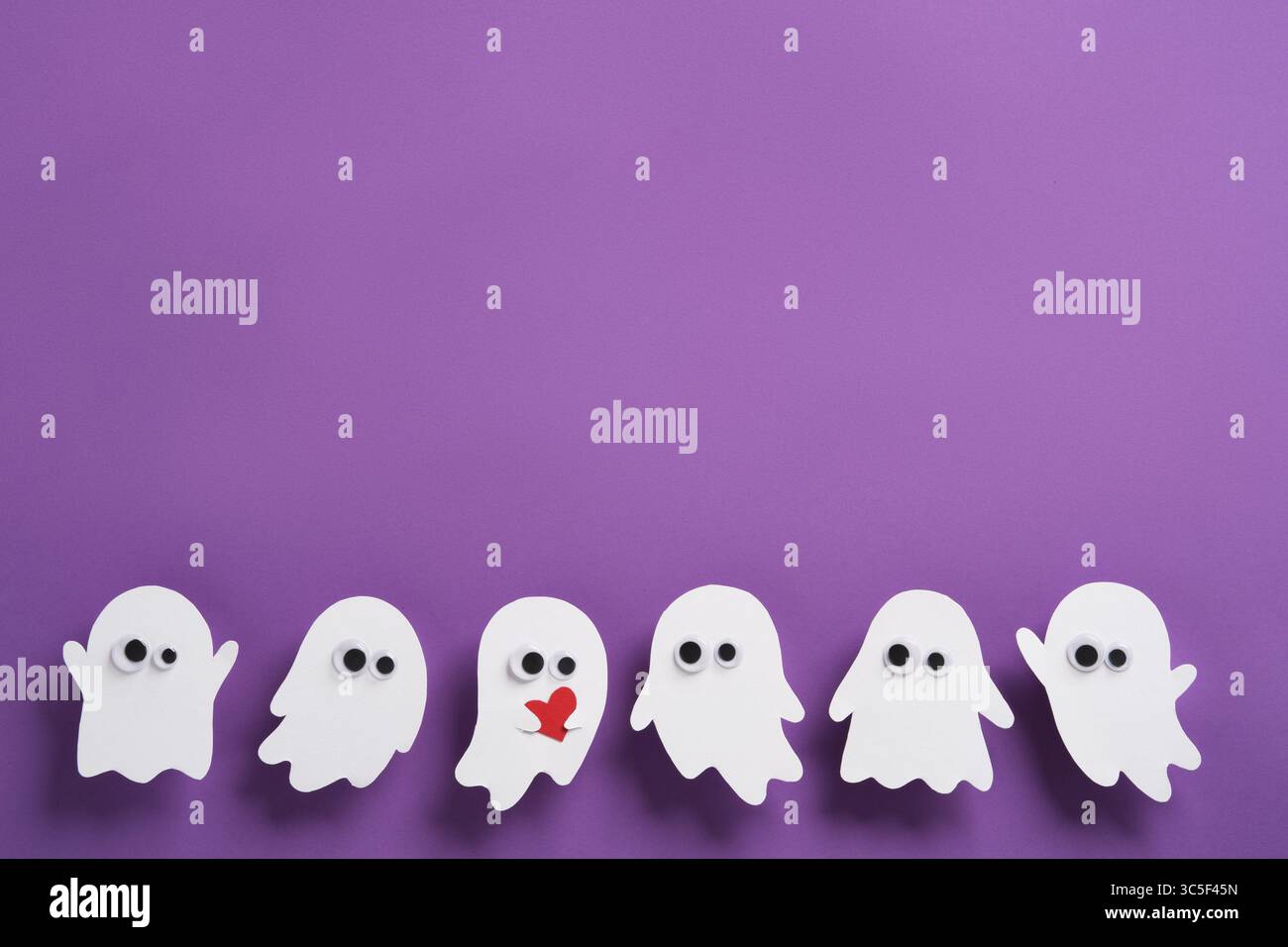 Simpatici fantasmi con occhi su sfondo viola, un fantasma con cuore rosso, banner orizzontale di Halloween, spazio per il testo Foto Stock