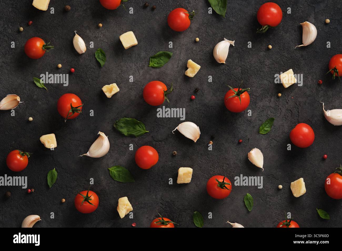 Background culinario con ingredienti italiani, pomodori, aglio, formaggio e basilico su sfondo scuro Foto Stock
