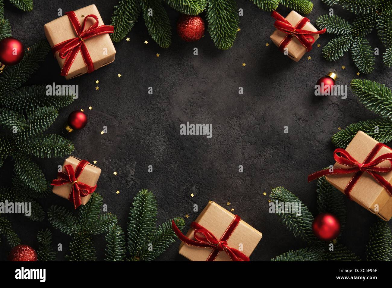Cornice natalizia con scatole regalo con nastri rossi e rami di pino su sfondo scuro. Inserire il testo. Foto Stock