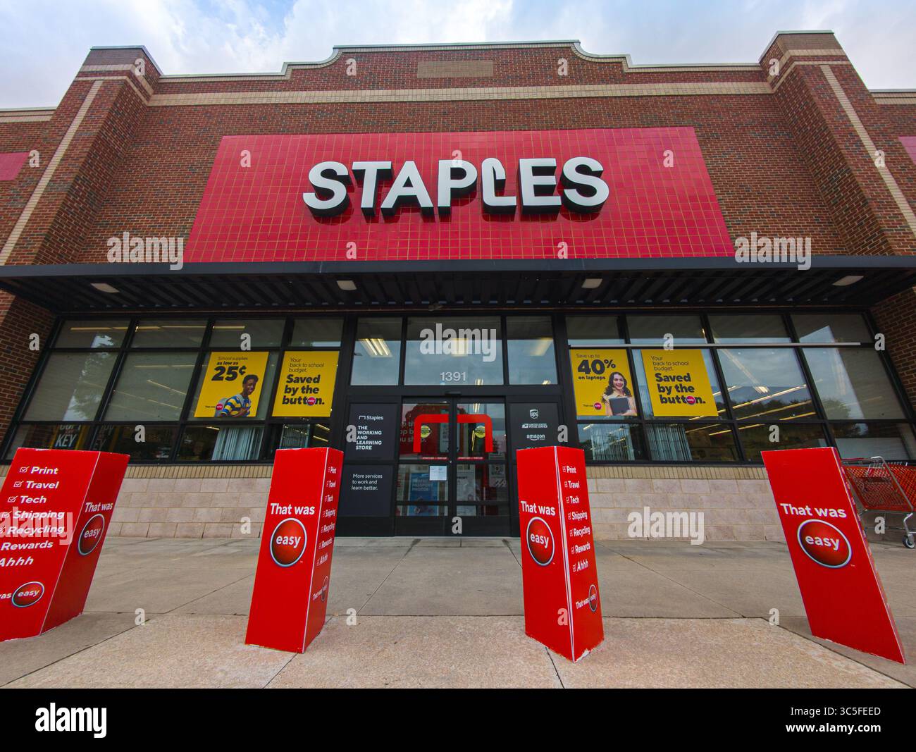 Logo Staples illuminato sul moderno punto vendita al dettaglio di forniture per ufficio - Immagine stock catturata con smartphone