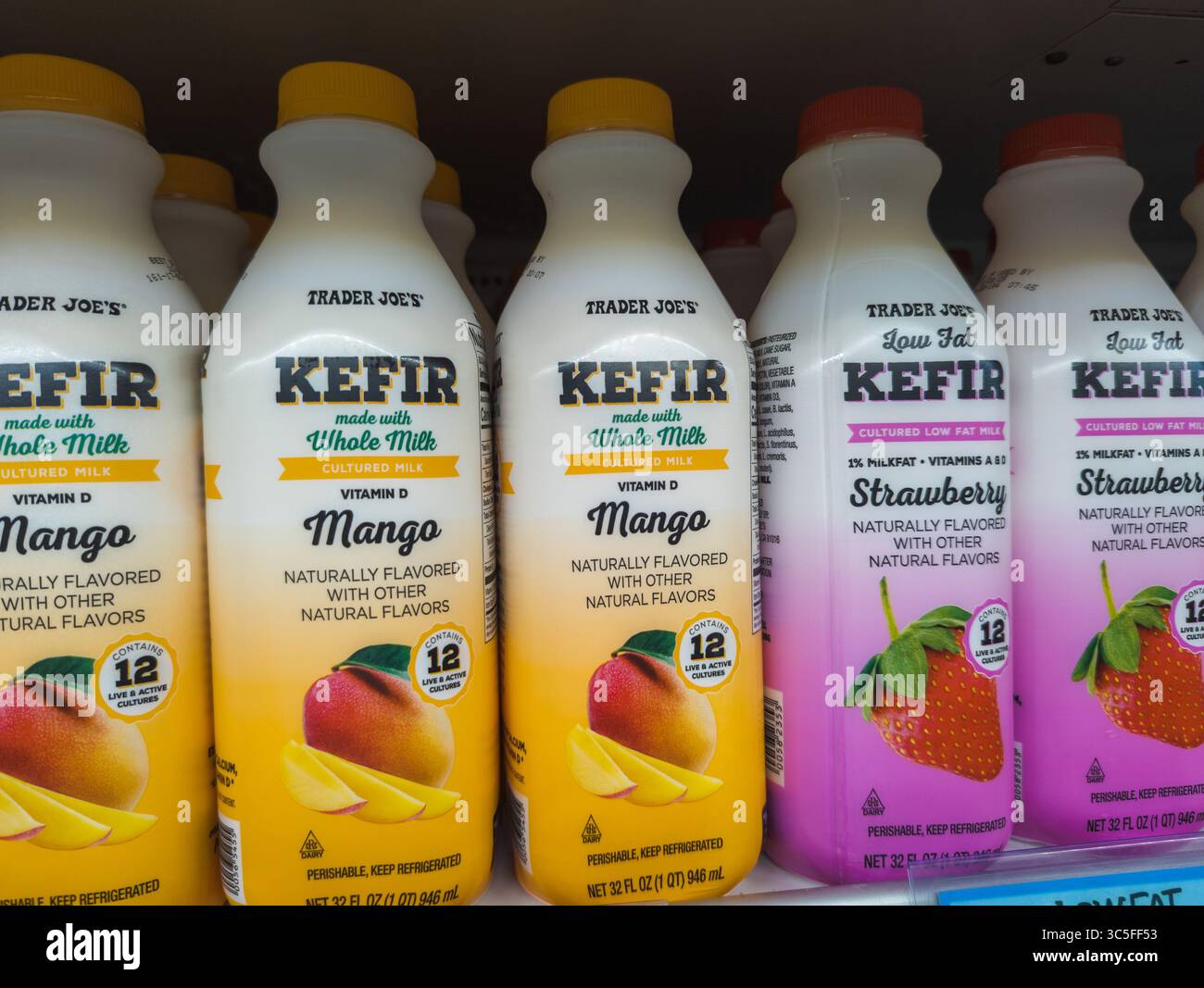 Bottiglie di kefir Trader Joes disposte in modo ordinato su un ripiano refrigerato con etichette Probiotic visibili Foto Stock