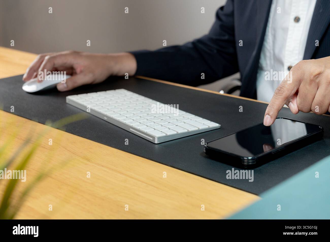 Un allegro dipendente d'ufficio che lavora alla sua scrivania in un ambiente d'ufficio moderno, rappresentando produttività e soddisfazione sul lavoro. Foto Stock