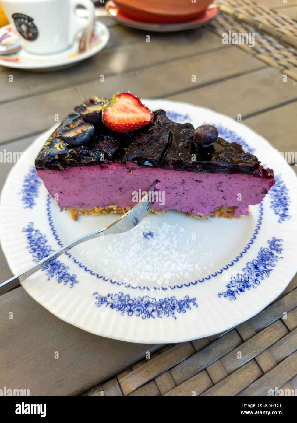 Un'appetitosa fetta di torta servita su un piatto con una tazza di caffè, ideale per una deliziosa esperienza di dessert Foto Stock