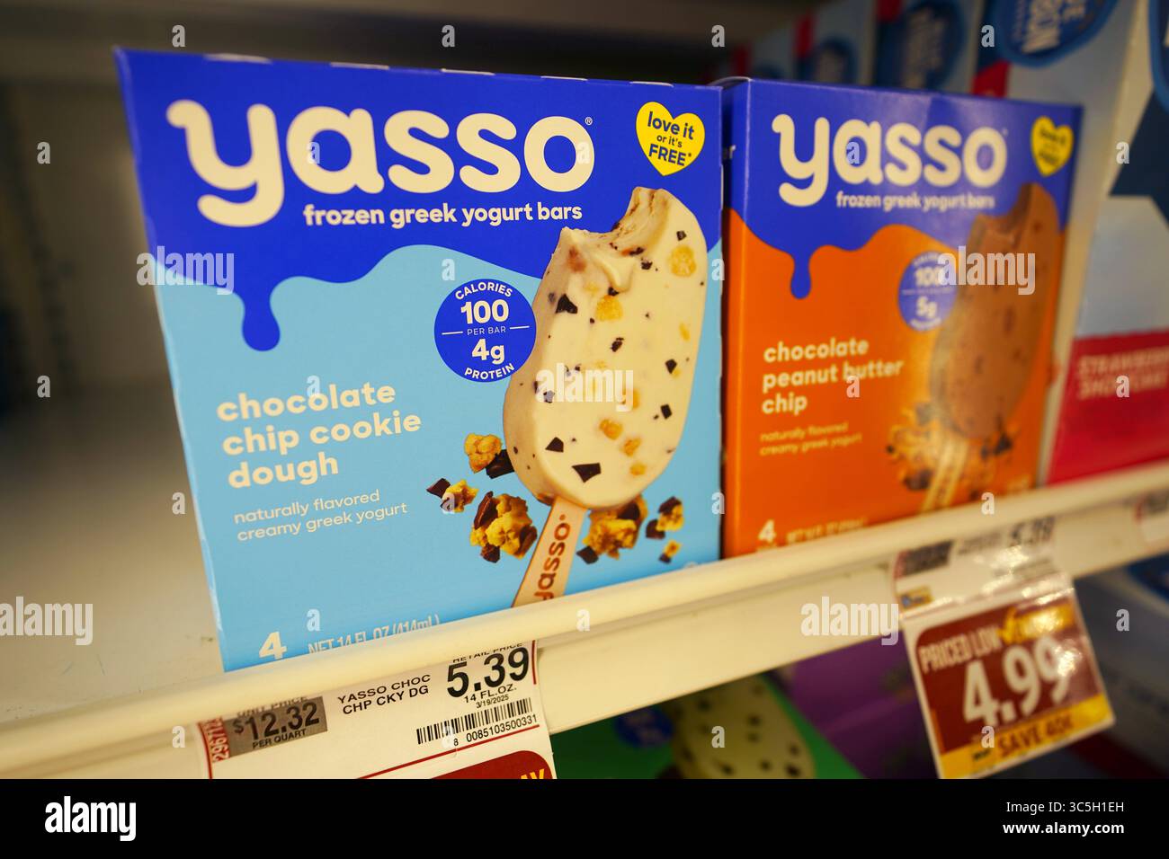Barrette di yogurt greco congelato Yasso elegantemente esposte sul ripiano del congelatore della drogheria Foto Stock