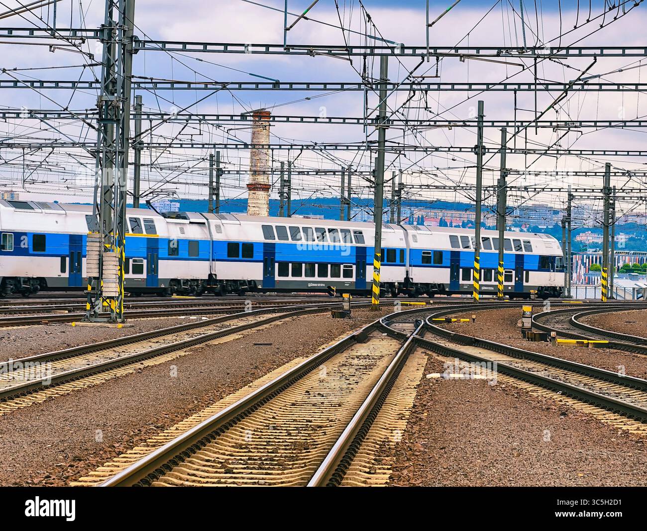 Binari ferroviari e linee elettriche aeree presso la stazione ferroviaria – Abstract Industrial background con Blue Passenger Train, ideale per sfondo, Web Design, pubblicità e uso digitale Foto Stock