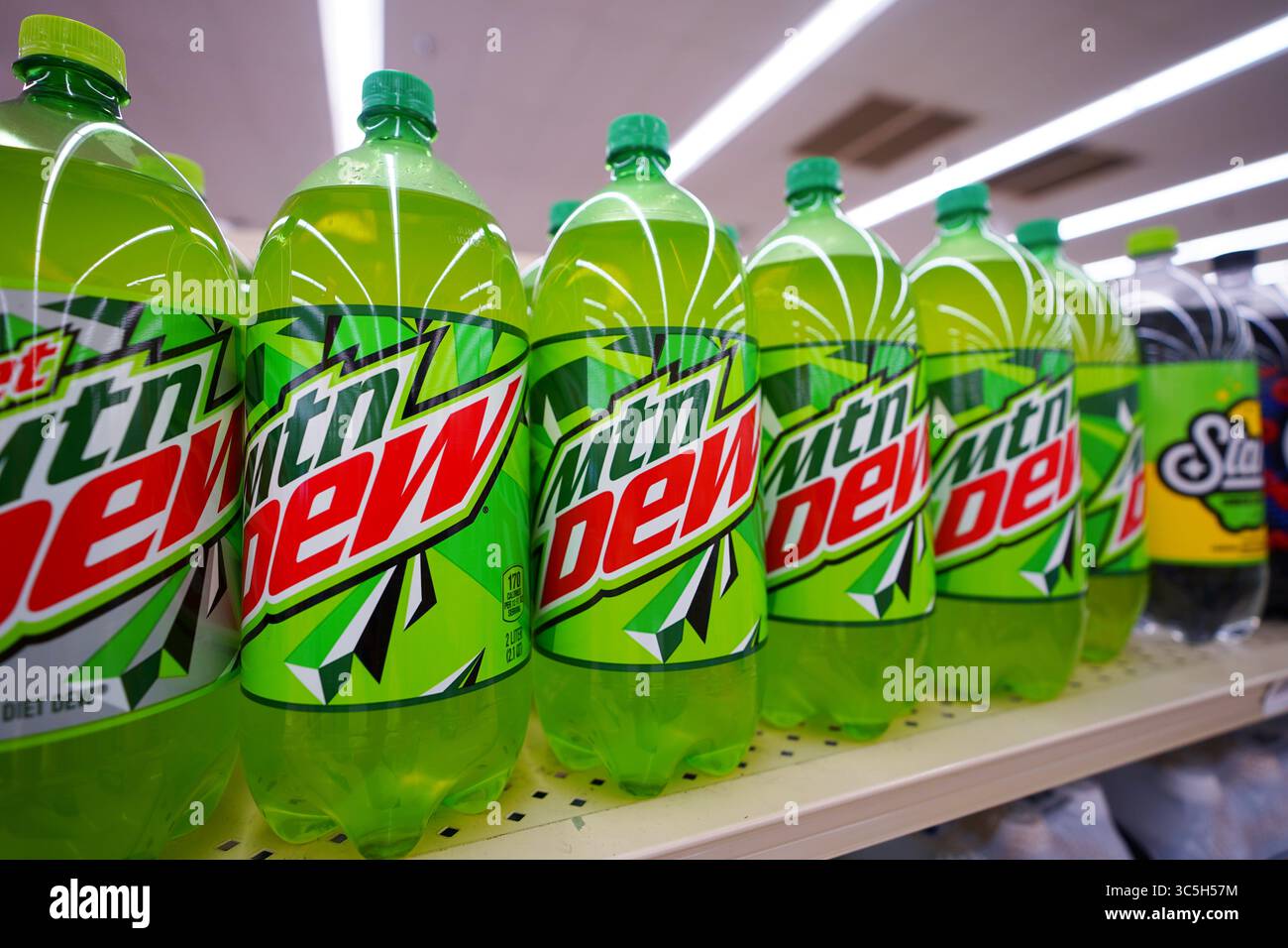 Bottiglie di bibite gassate Mountain Dew di varie dimensioni disposte in modo ordinato sullo scaffale del punto vendita Foto Stock