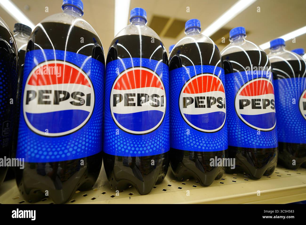 Bottiglie in soda Pepsi in varie misure da litri disposte in modo ordinato sul ripiano del punto vendita Foto Stock